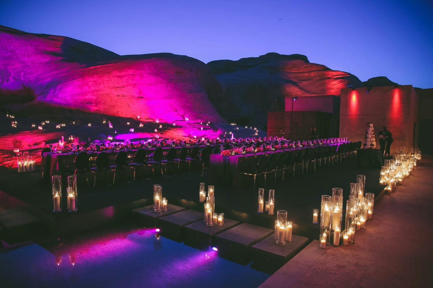 Wedding night reception in desert with candlelight and purple and red lighting projected onto surrounding canyons | PartySlate