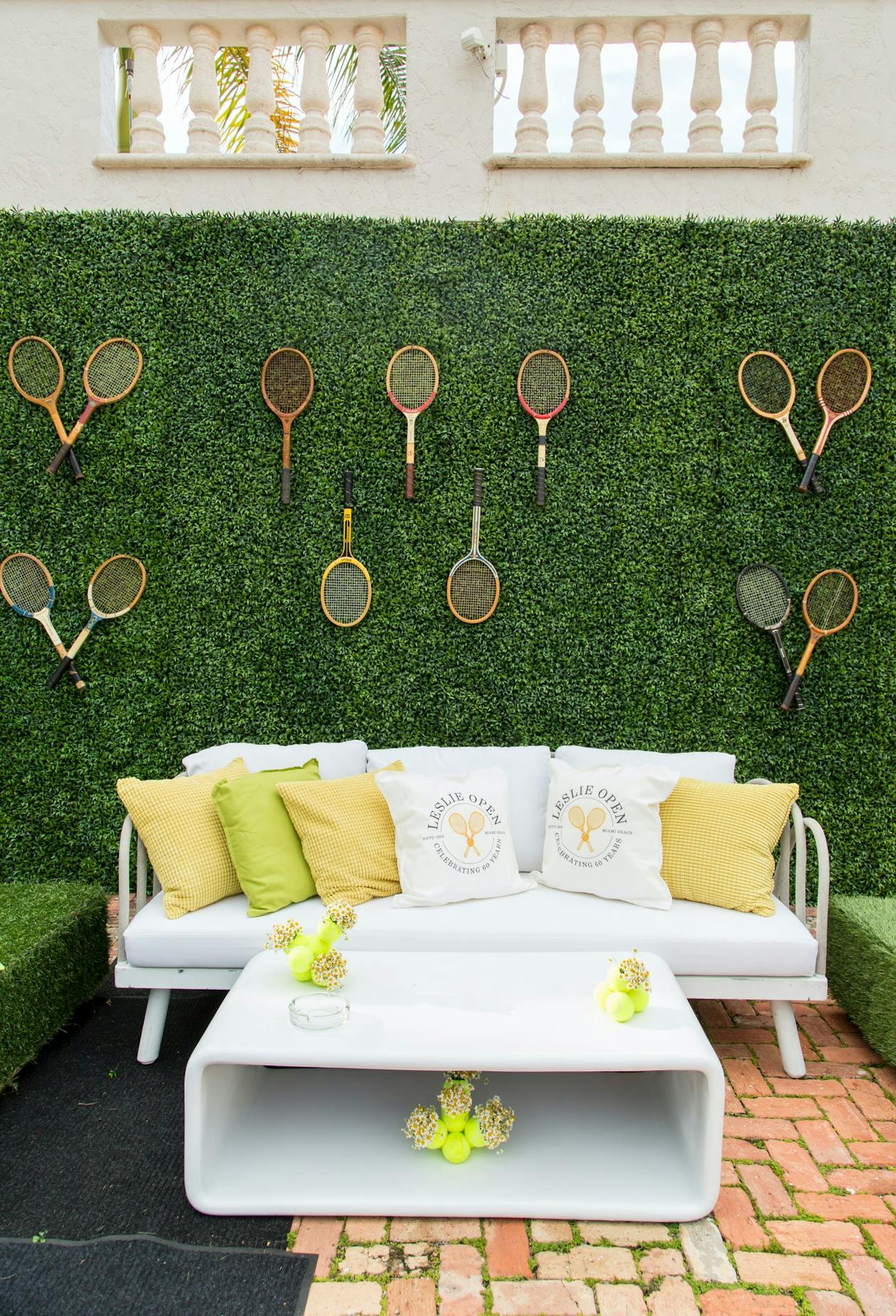 Tennis Tournament Themed Party With Tennis Racket Greenery Wall and Couch in Front | PartySlate