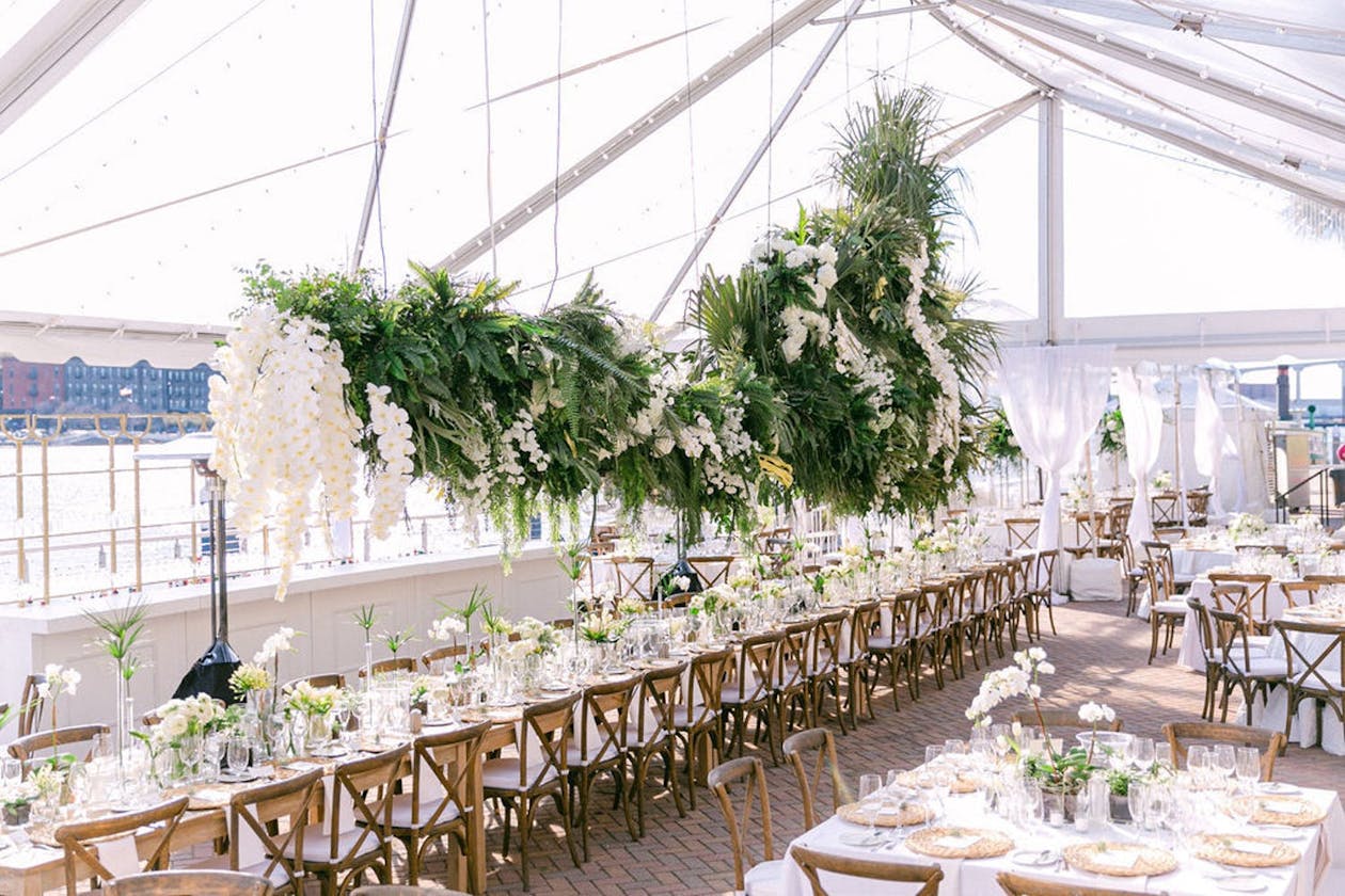 Transparent wedding tent with suspended tropical organic greenery and white orchids | PartySlate