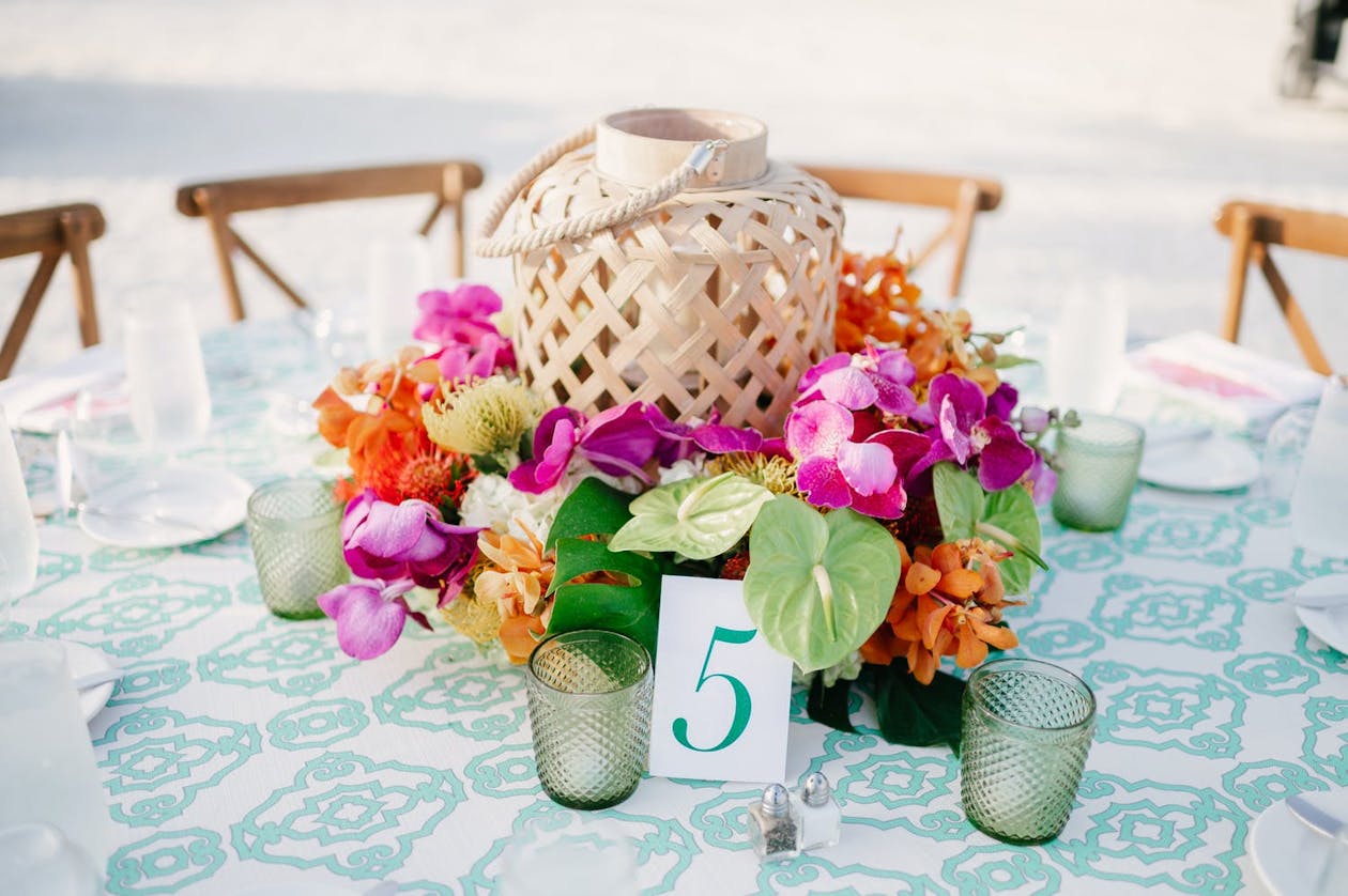 Wicker lantern surrounded by colorful tropical flowers | PartySlate