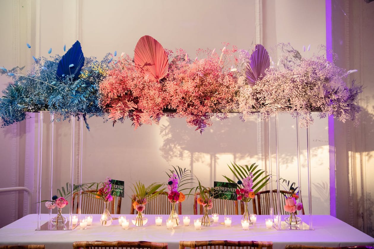 Boho tropical wedding centerpieces with blue to pink to purple ombré baby's breath and dyed palm leaves | PartySlate