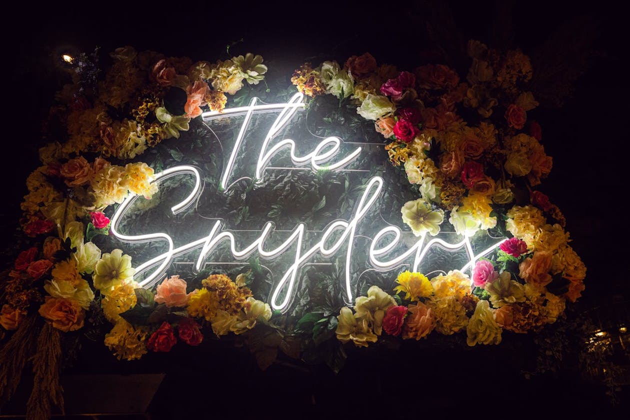 Last Name Neon Sign Surrounded in Yellow and Red Flowers | PartySlate