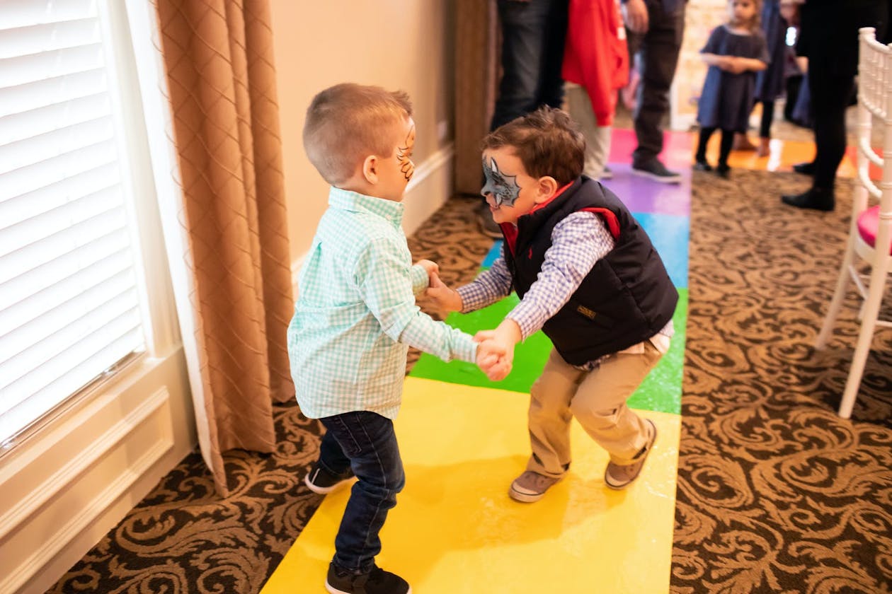 Two little boys hold hands on a Candy Land-style track | PartySlate