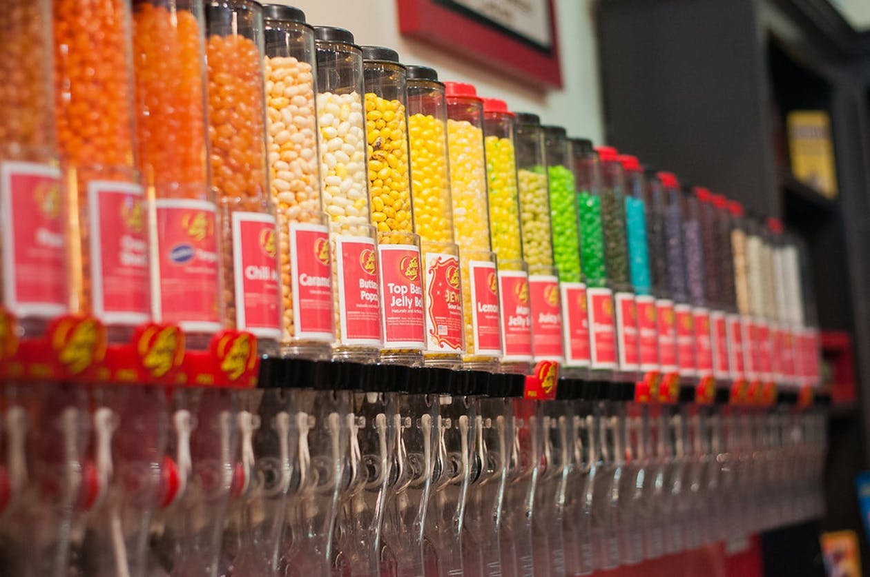 Candy shop party with jelly bean canister station in rainbow formation | PartySlate