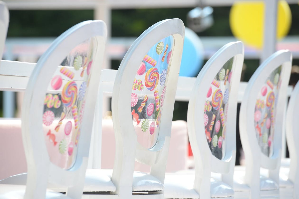 White party chairs with clear backing decorated with candy illustrations | PartySlate
