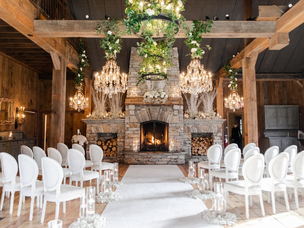 Micro Wedding At Home With Fireplace As Focal Point And Chandeliers Hanging From Ceiling With White Chairs | PartySlate