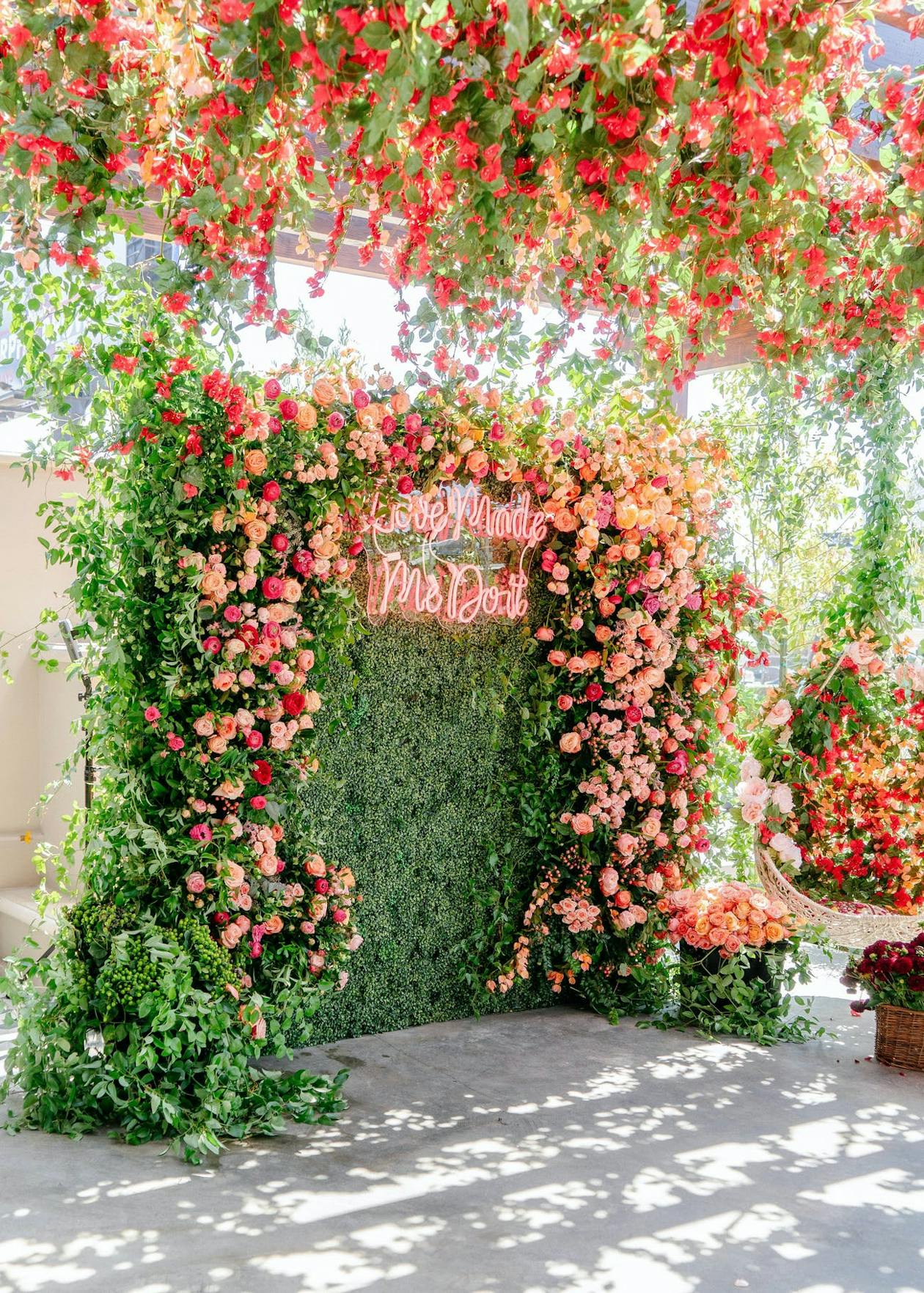 Stunning Greenery Wall with Pink Flowers Hanging Around Neon Sign | PartySlate