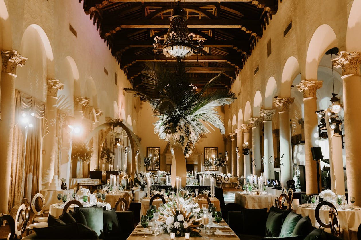 Wedding reception with towering ceilings and tropical centerpieces with boho-style pampas grass | PartySlate