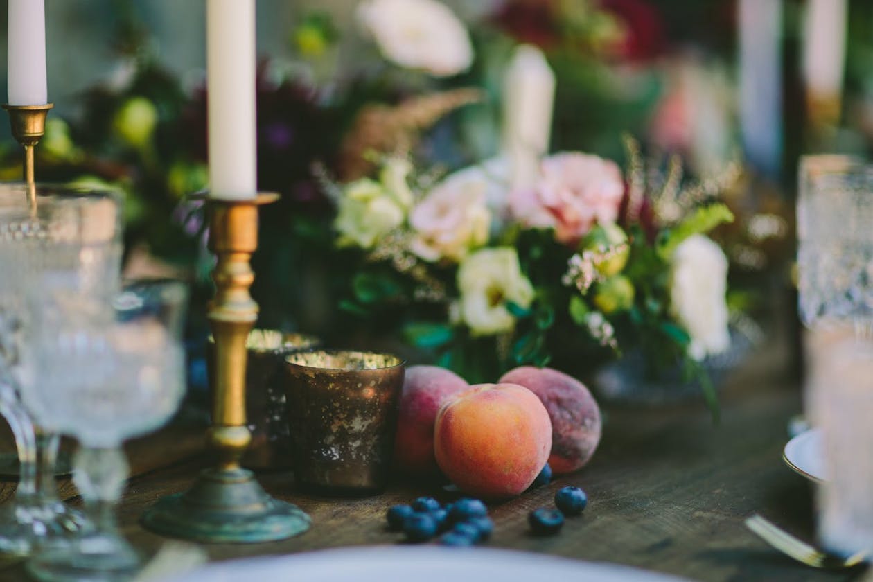 Tropical wedding reception with gold candle holders, nectarines, and blueberry centerpieces | partySlate