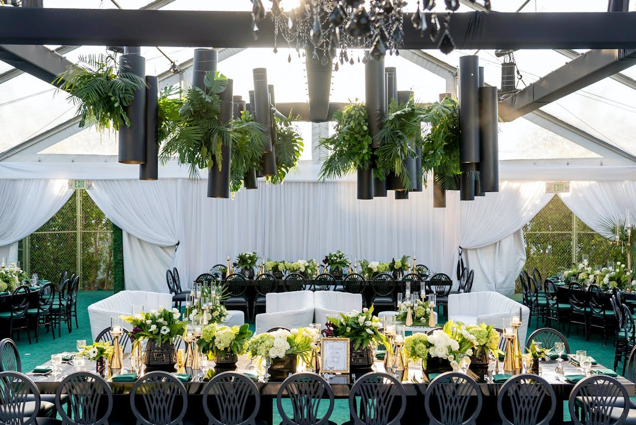 Moder tropical tented wedding with suspended greenery and black fixtures | PartySlate