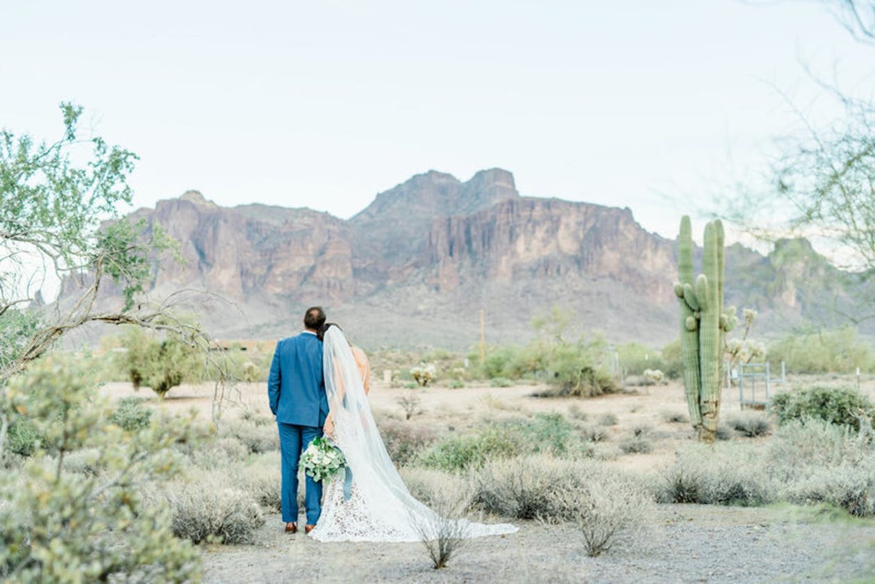 Bride leans on groom's shoulder as they stare at the vast desert landscape | PartySlate