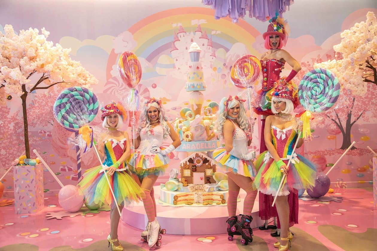 Five women in colorful wings, tutus, and roller skates at Candy Land kid's birthday party | PartySlate
