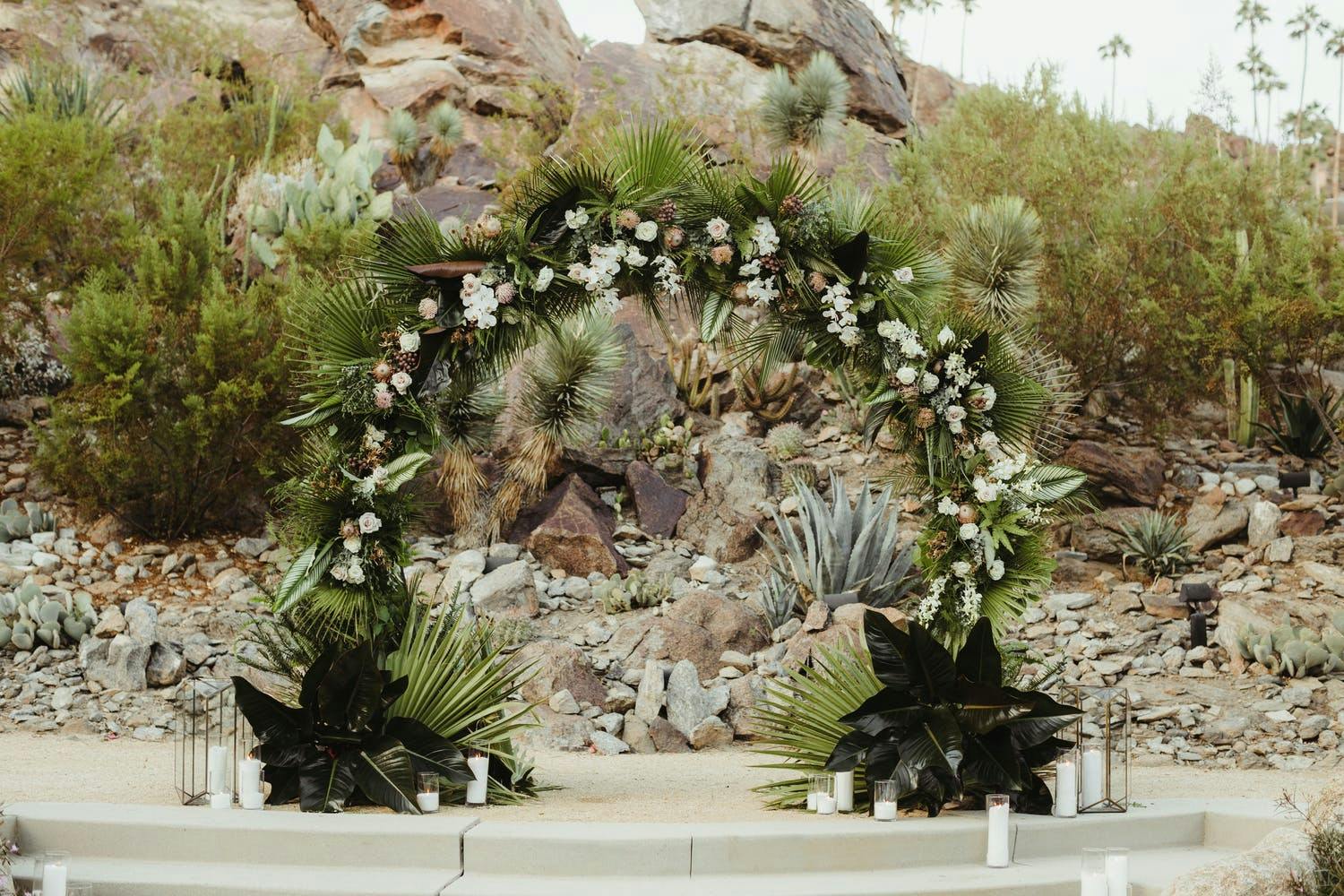 Tropical wedding arch against desert backdrop | PartySlate