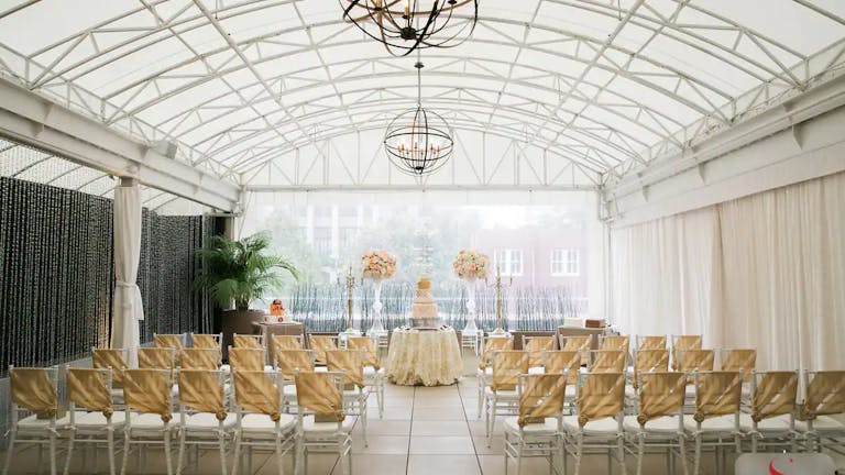 Veranda Space Within The Sam Houston Hotel With Bright Windows and Floral Arrangements at front | PartySlate