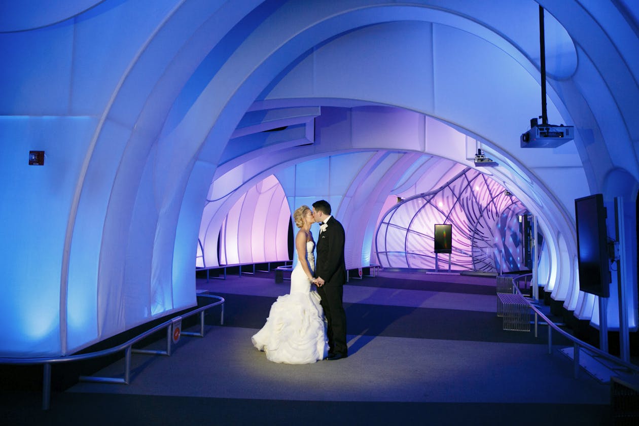 Wedding At Planetarium With Couple Standing In Hallway WIth Blue and Purple Lighting | PartySlate