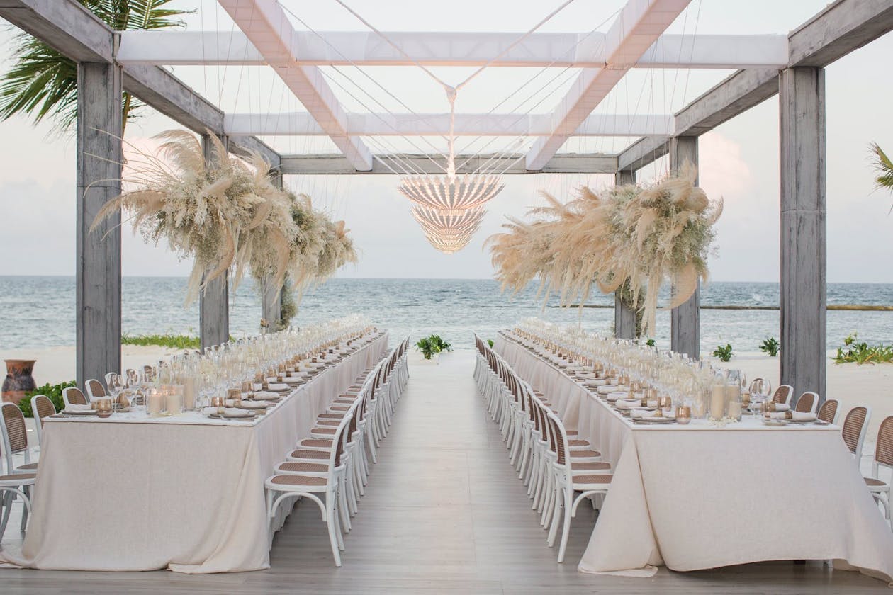 White beach wedding reception with pampas grass centerpieces | PartySlate
