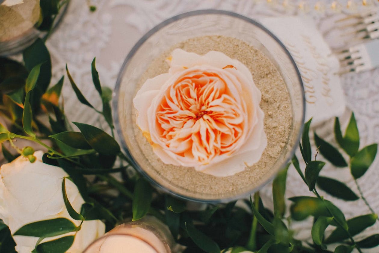 Cup filled with sand and peach flower for wedding table décor | PartySlate