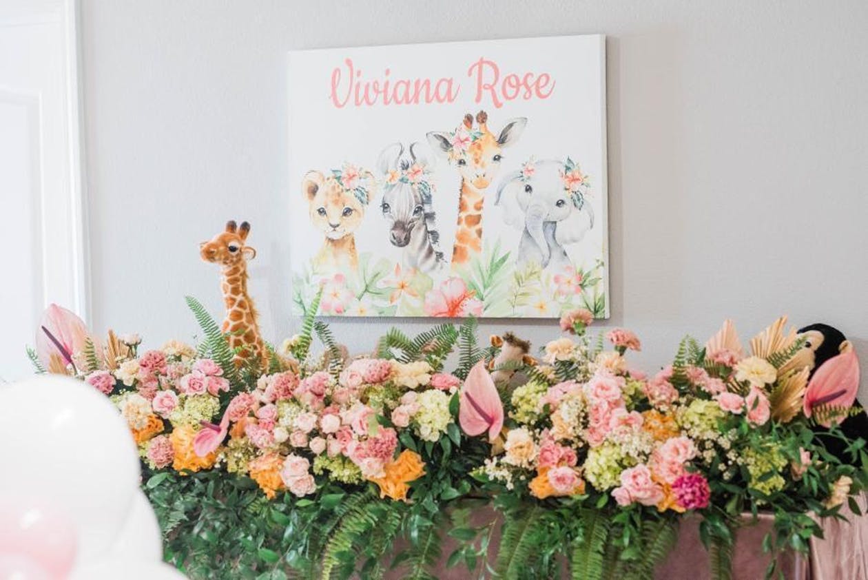 Pink safari baby shower signage and pink and orange floral display | PartySlate