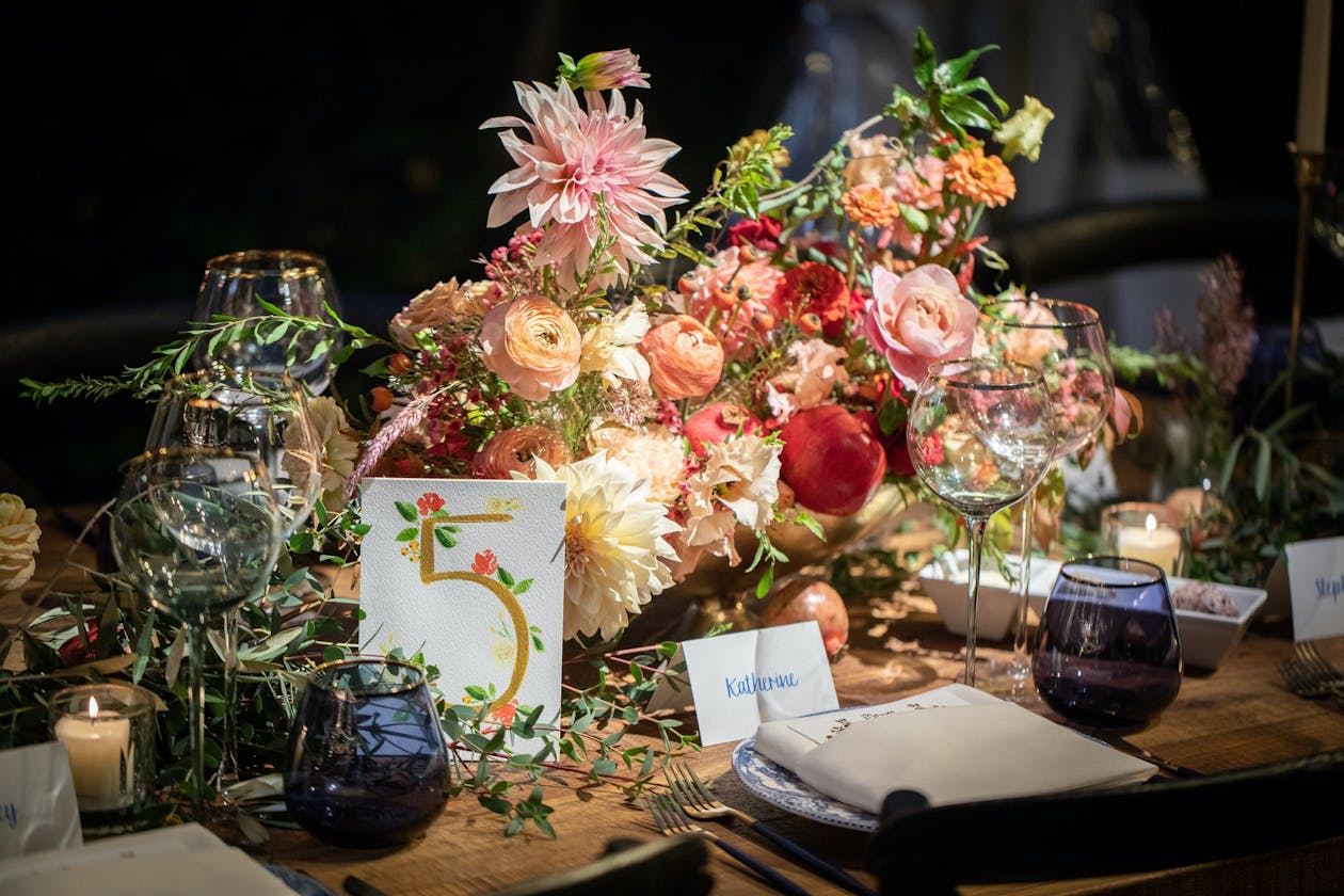 Pink, red, and peach flower centerpiece with watercolor table number | PartySlate