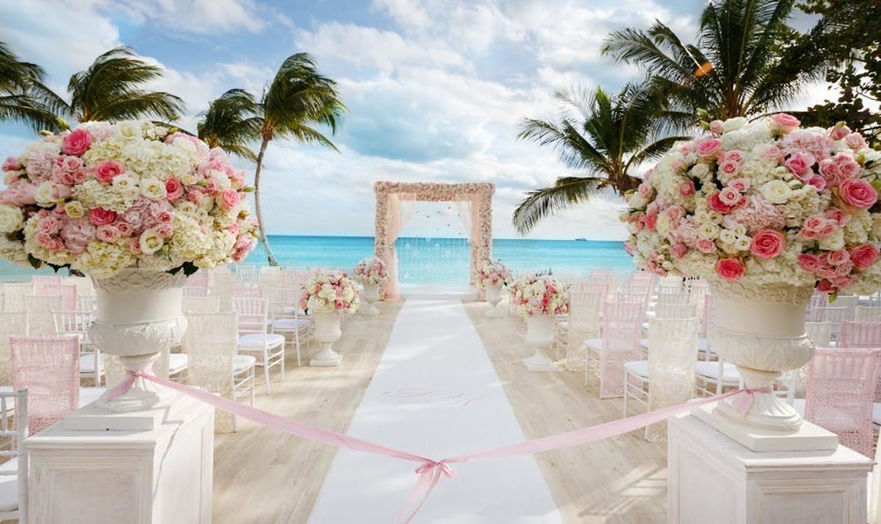 Beach wedding ceremony with white and pink flowers | PartySlate