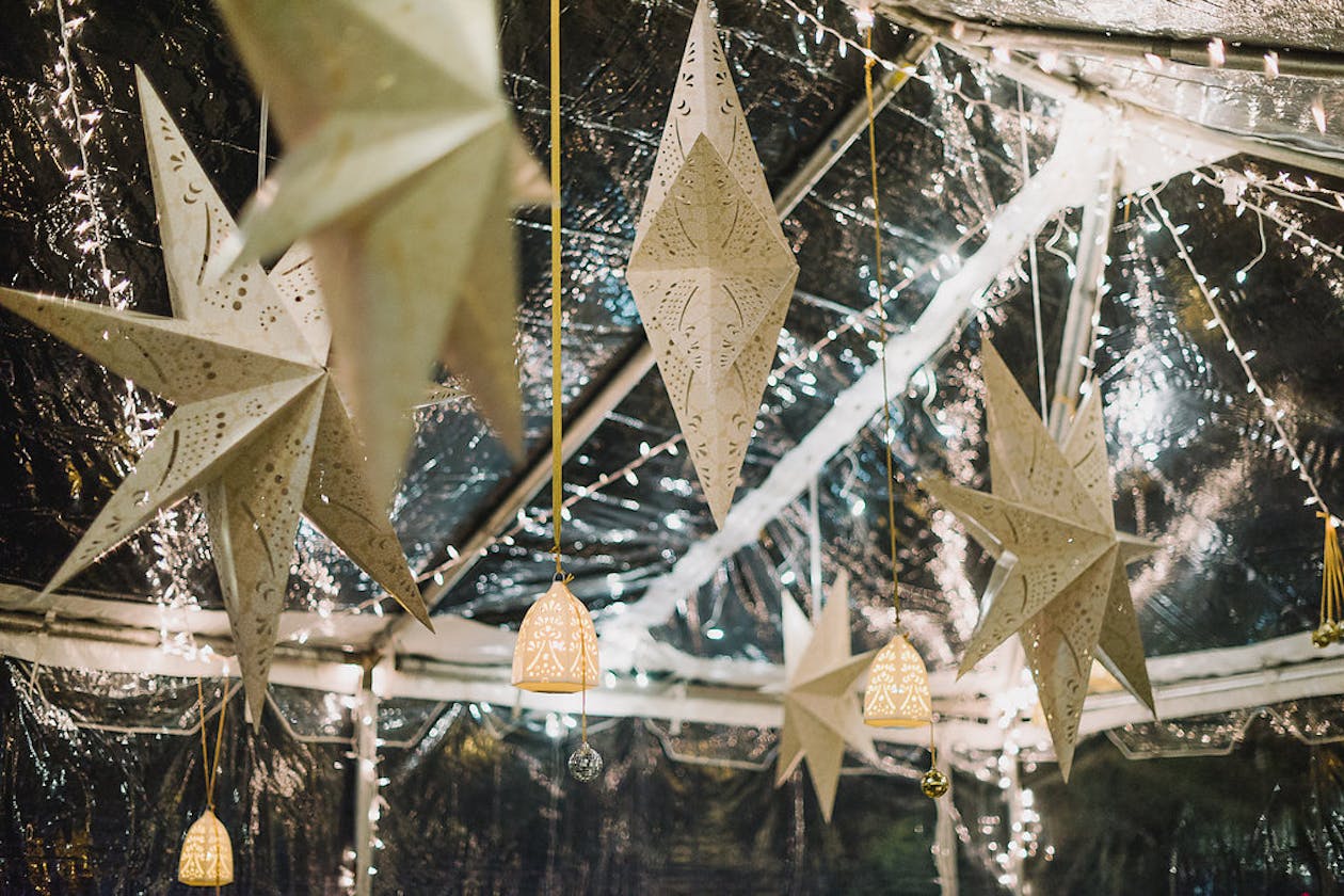 star lanterns hanging from tent ceiling at wedding | PartySlate