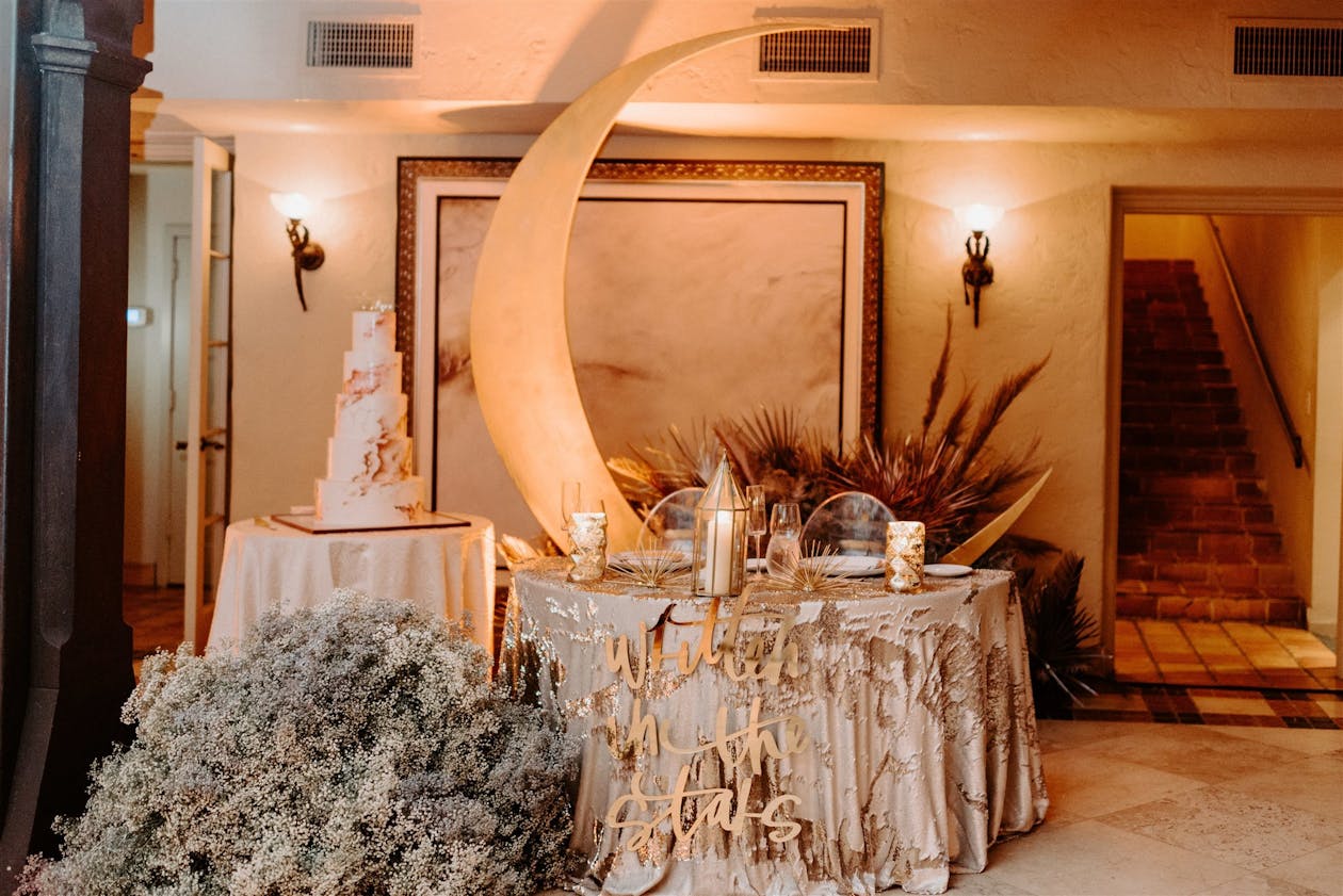 celestial themed food and drink table with moon back drop and tiered cake | PartySlate