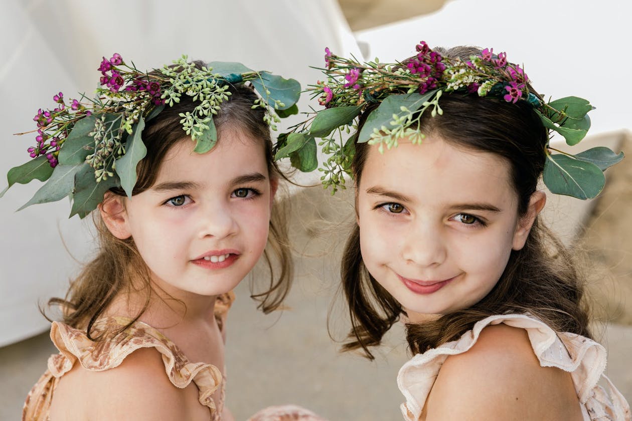 Two little girls wear maroon floral crows for beach wedding | PartySlate