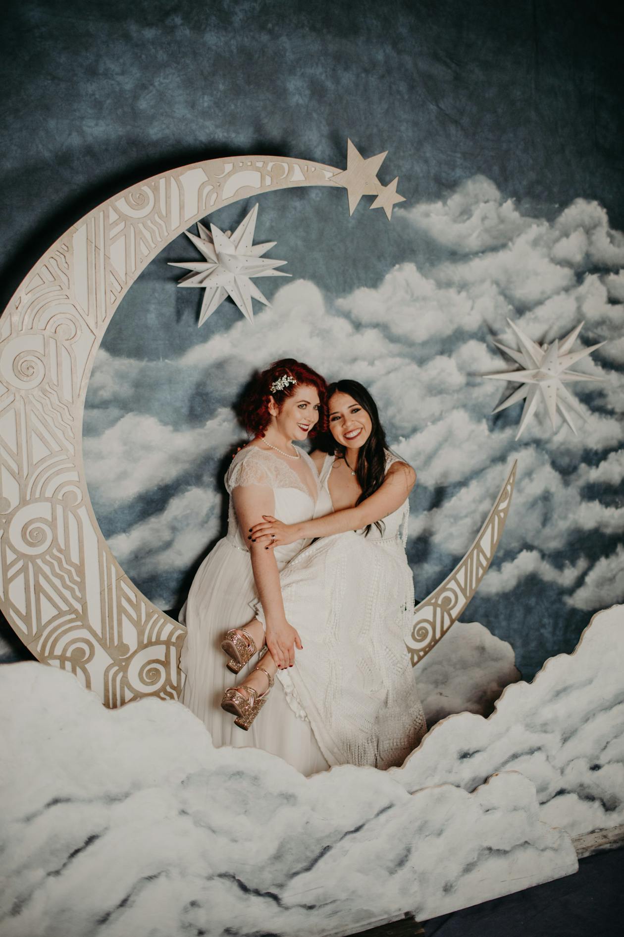 couple posing and hugging on moon backdrop at wedding | PartySlate