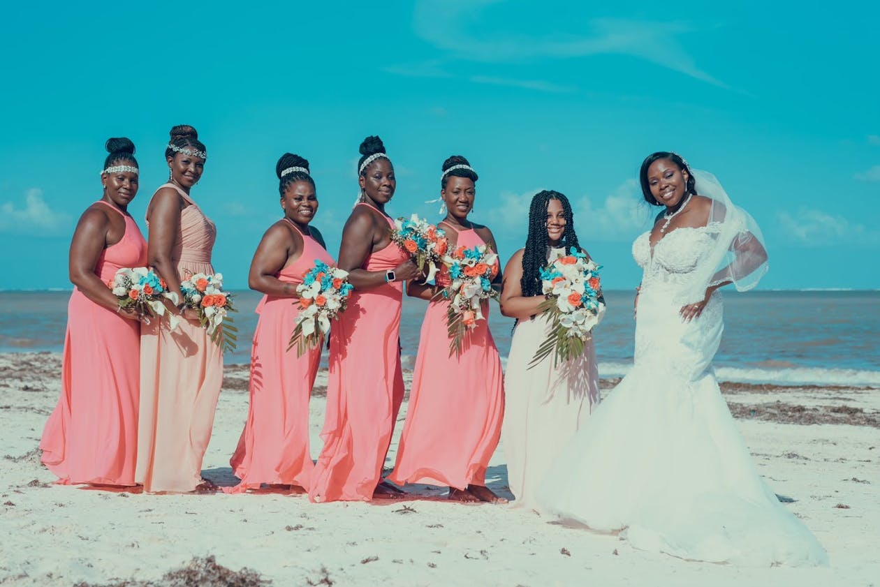Beach wedding with bridesmaids in coral dresses with teal and coral bouquets | PartySlate