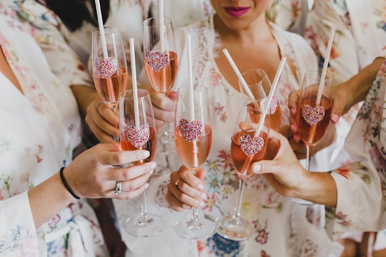 Bridesmaids hold Champagne flutes decorated with sprinkle nonpareils | PartySlate