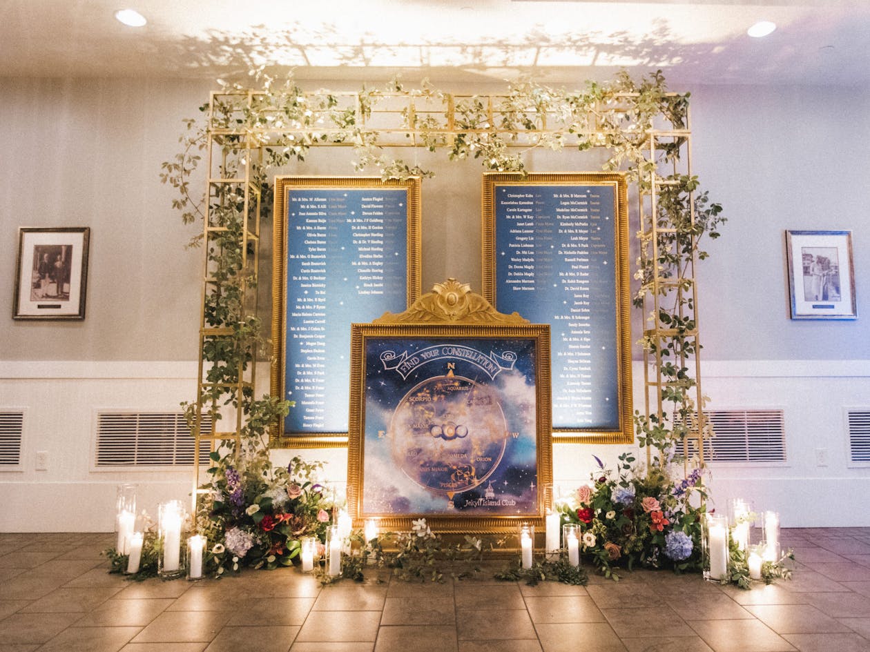 celestial themed seating chart at wedding in gold frames with greenery and candles around it | PartySlate
