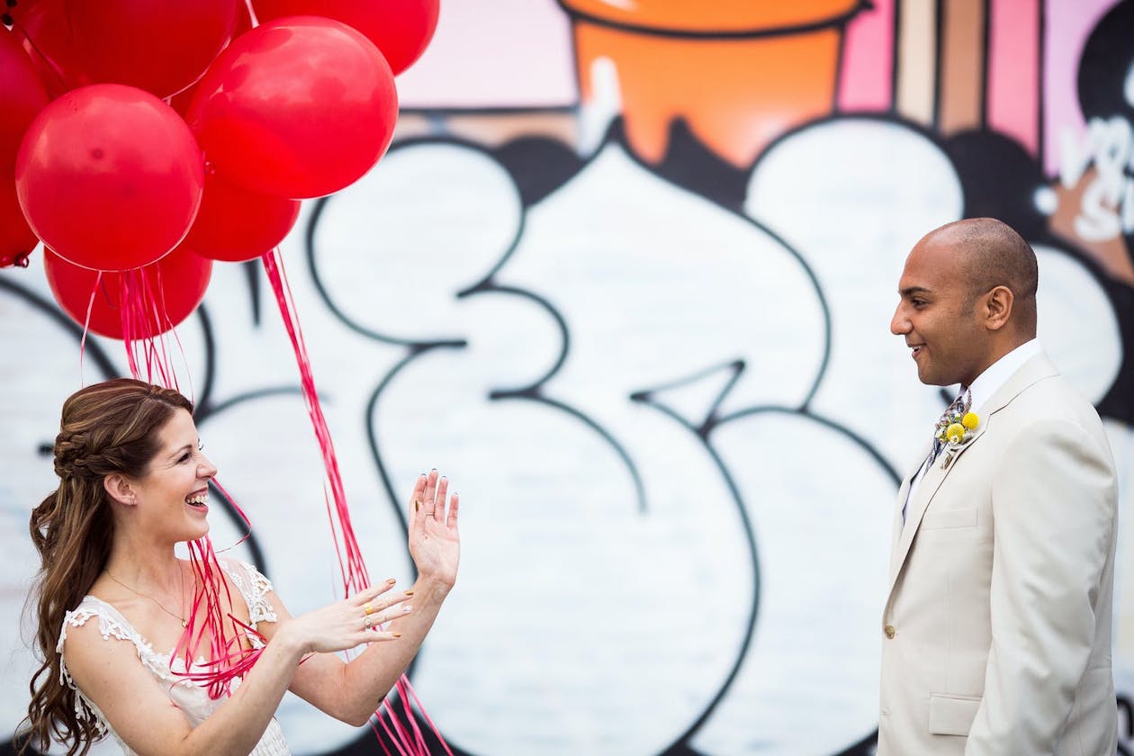 First look with red balloons and bright and unique wedding | PartySlate