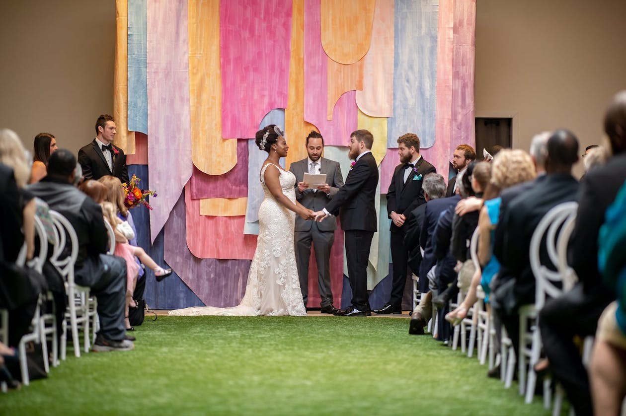 Wedding ceremony against funky and colorful backdrop | PartySlate