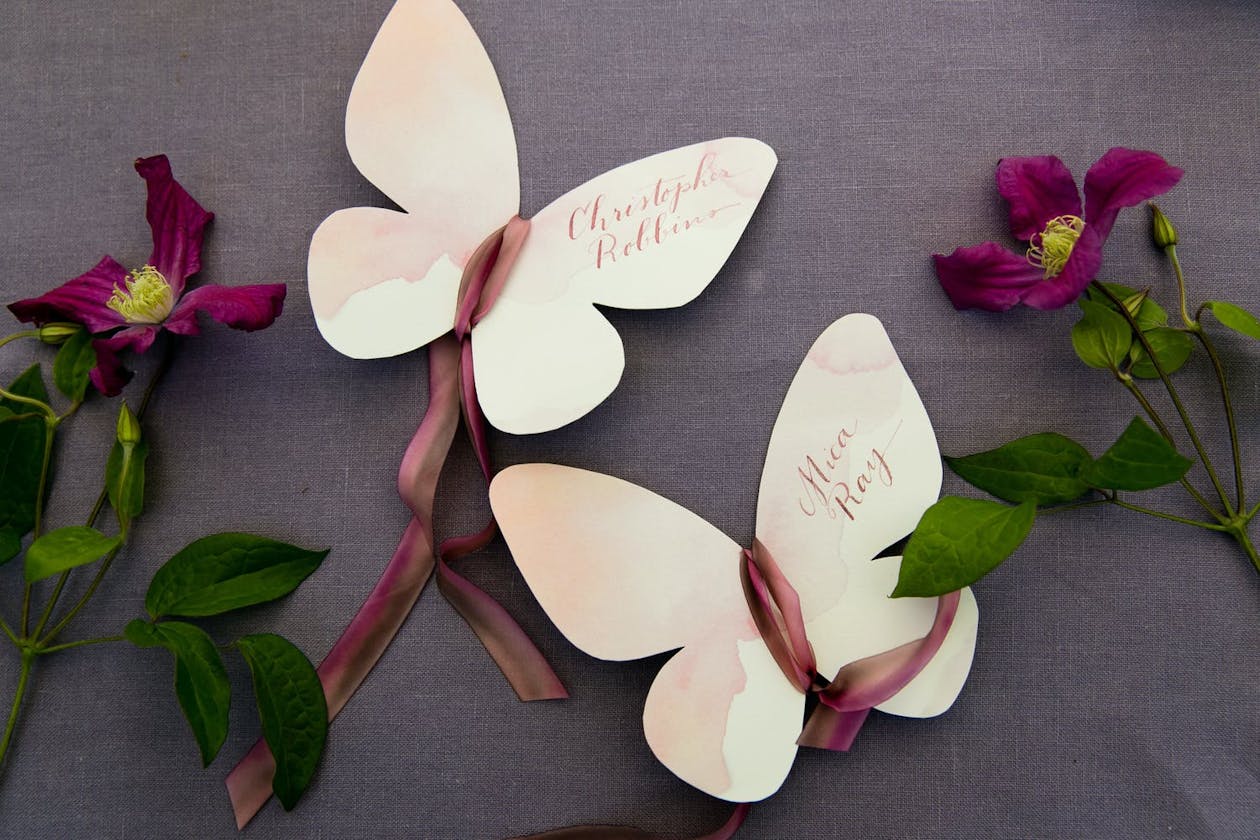 Butterfly escort cards with maroon ribbons | PartySlate