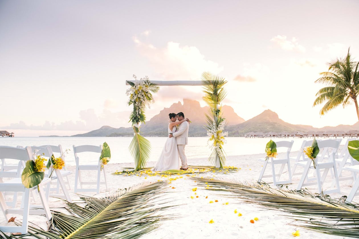stunning tropical wedding in bora bora four seasons with couple at alter and plam leaves as décor | PartySlate