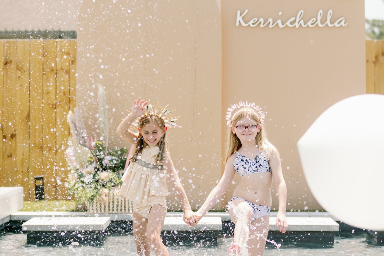 two little girls running into the pool at birthday party in front of birthday sign | PartySlate