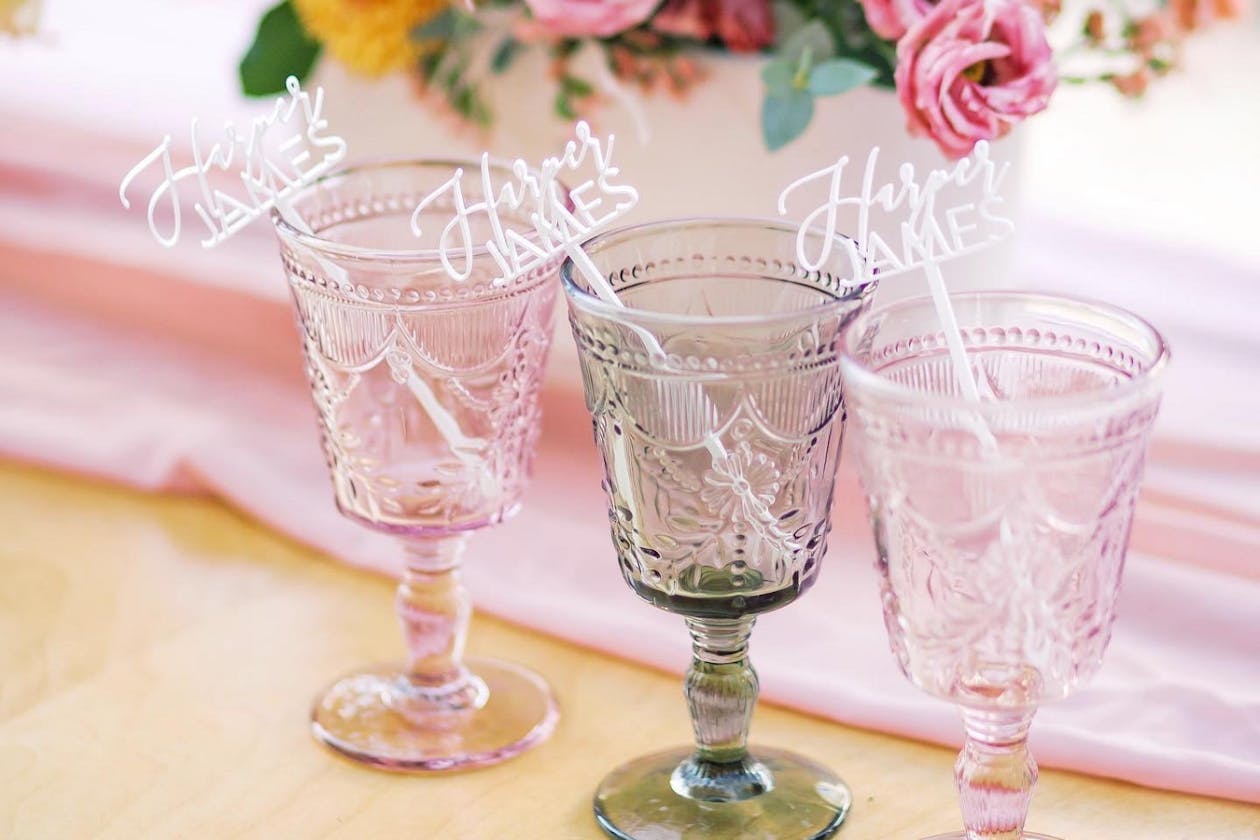 colored glassware sitting on a table with flowers in the background | PartySlate