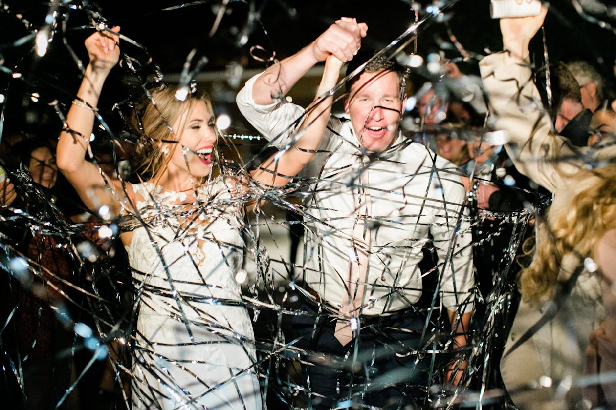 silver streamers being thrown at wedding couple leaving their wedding reception at night | PartySlate