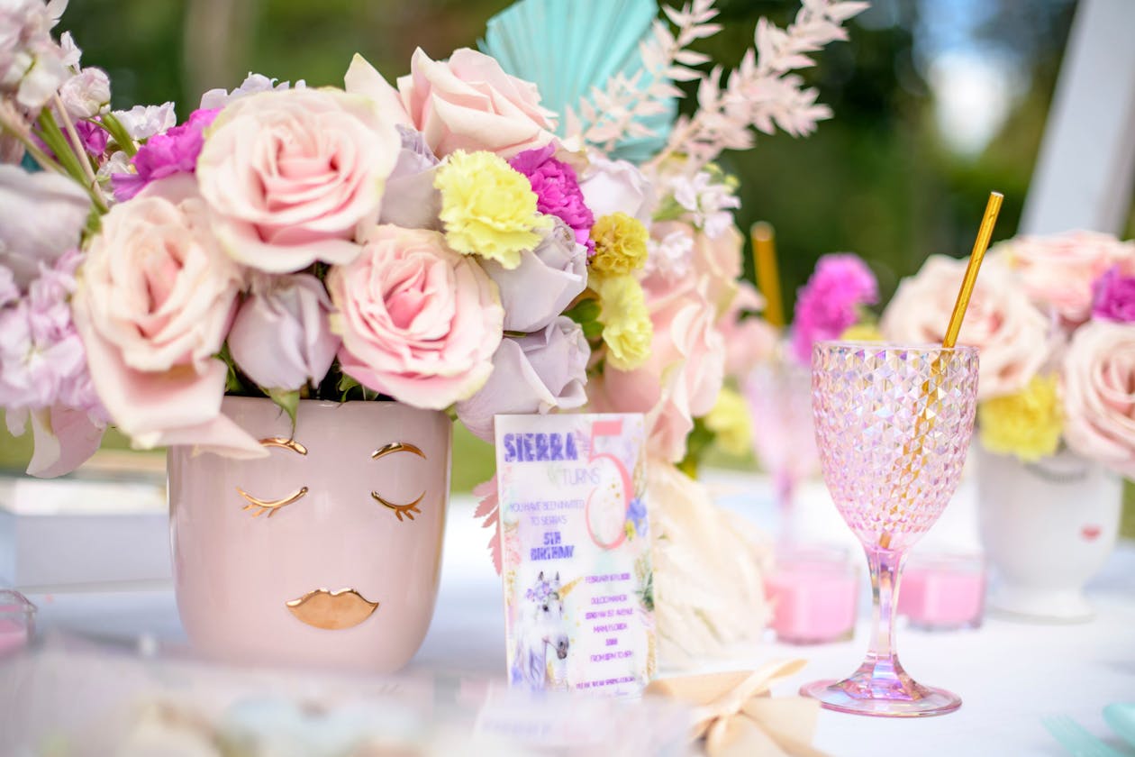 pastel colored glassware on a table with flowers in the back for a birthday party | PartySlate