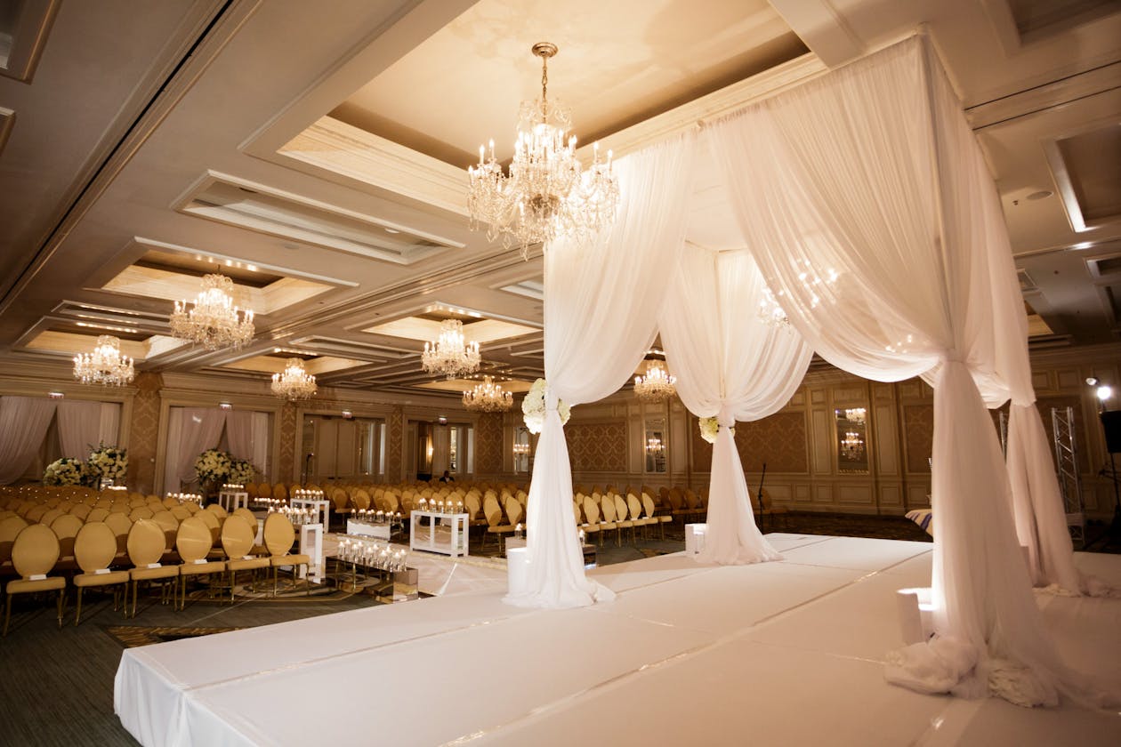 Classic squared arch with white drapery on a raised platform inside | PartySlate