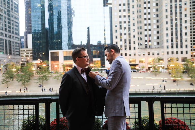 couple standing outside their chicago wedding venue pinning boutonnières on each others jackets | PartySlate