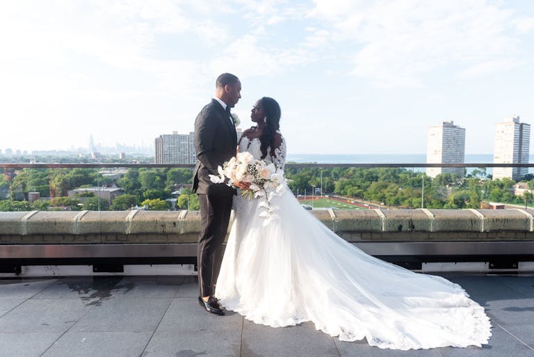 Outdoor wedding in Chicago with bride and groom posed on the terrace in wedding dress and tuxedo | PartySlate
