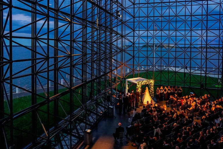 Wedding at JFK museum with couple at alter and guests seated at night | PartySlate