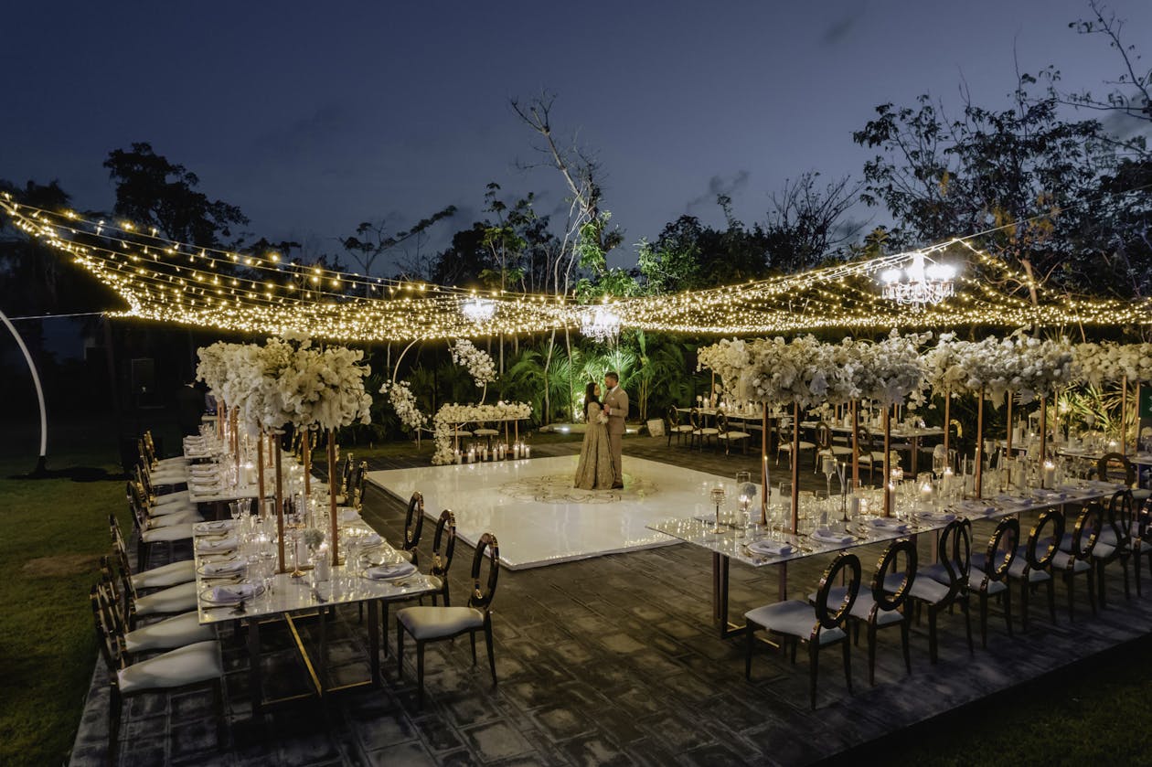 Outdoor wedding with string light tenting and tables surrounding dance floor | PartySlate