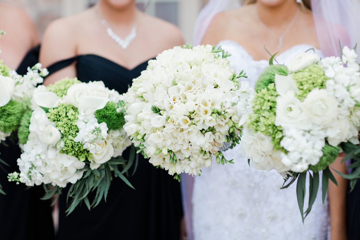 White floral bouquets with greenery held by the bride and her bridesmaids | PartySlate