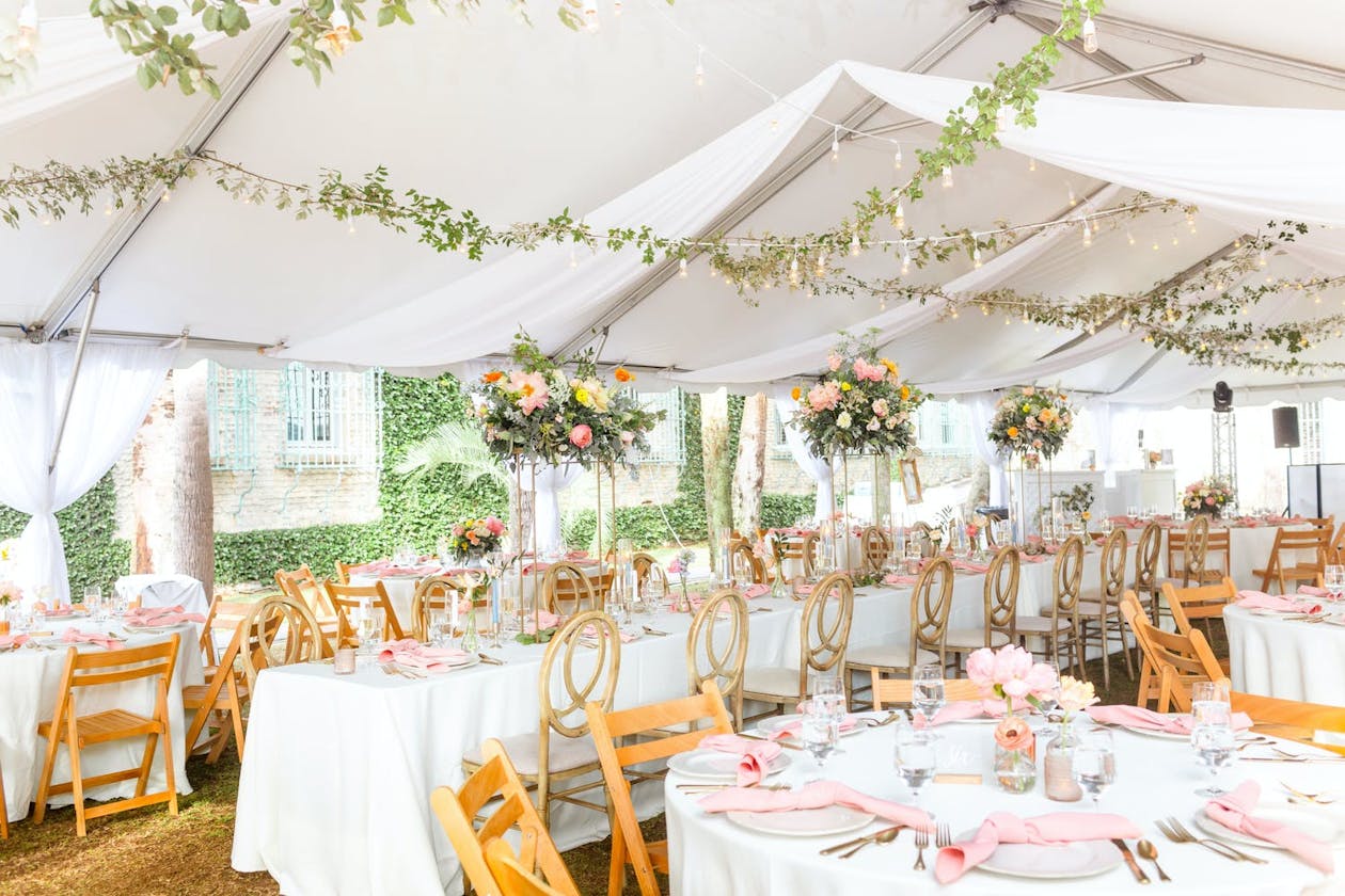 Summery garden wedding tent with pink flowers and greenery | PartySlate