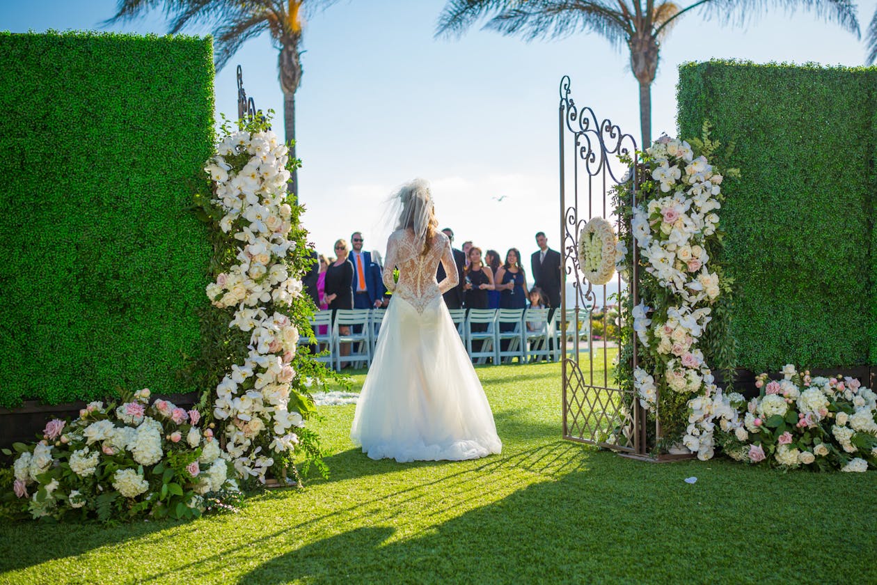 Bride walks through floral covered gates at fairytale wedding | PartySlate