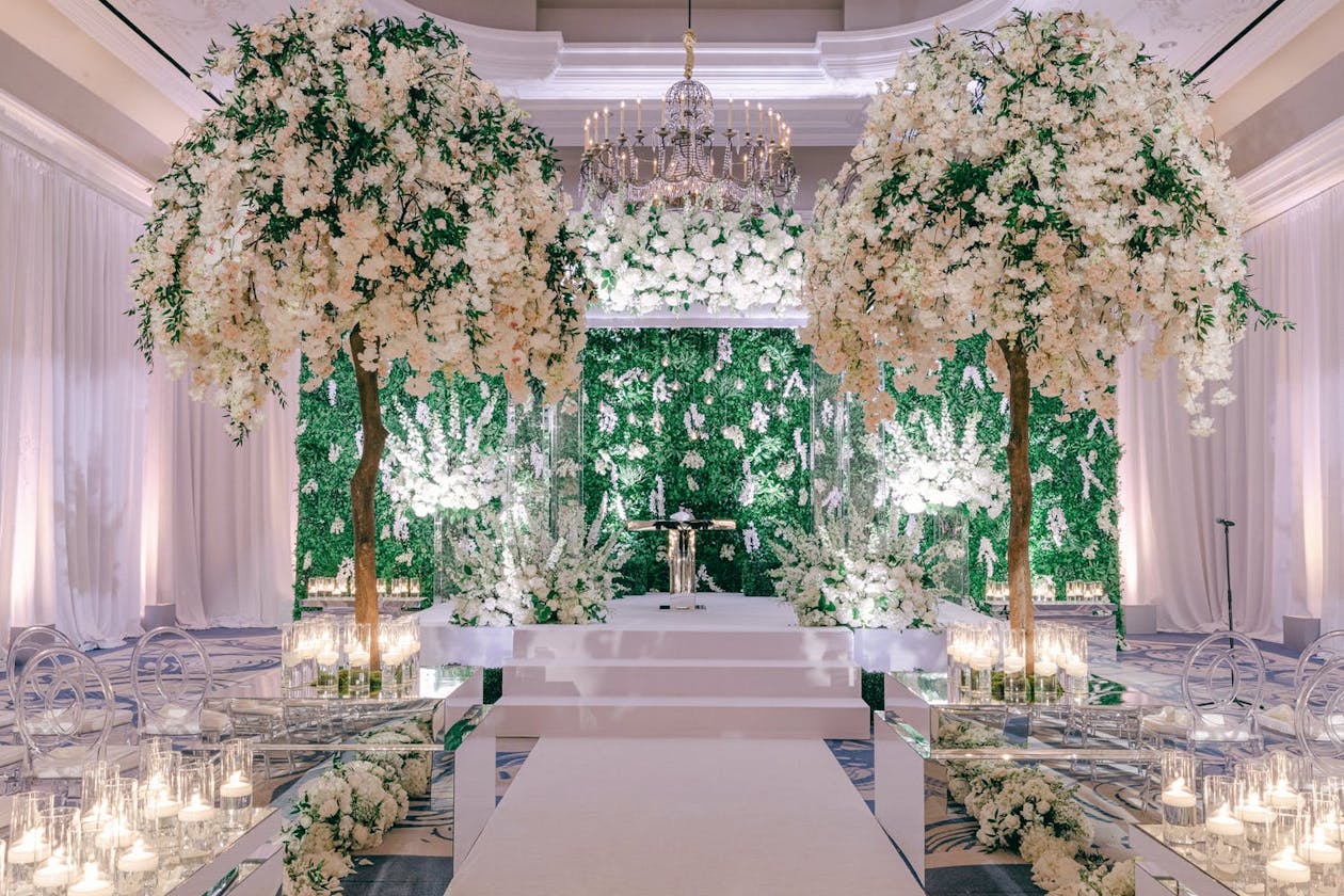Ballroom wedding ceremony with white flowers and boxwood backdrop | PartySlate