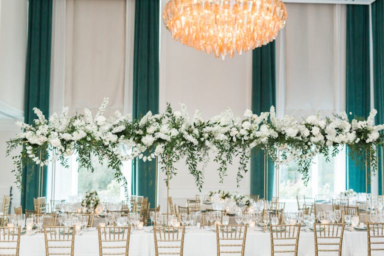 Green and white fall Boston wedding with raised centerpieces on tables with green and white drapes behind the tables | PartySlate