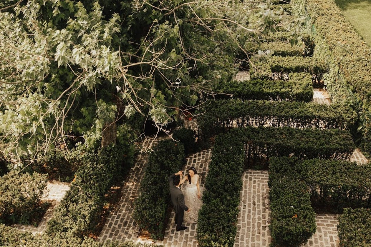 Couple walks through hedge maze at garden wedding venue | PartySlate
